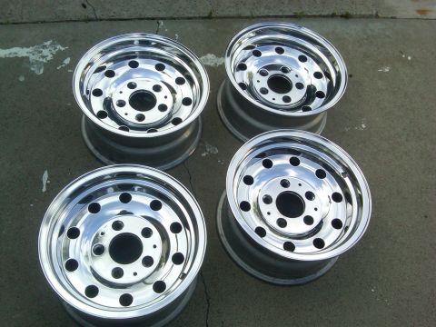 1986 Ford Bronco - Four shiny chrome wheels are displayed on a concrete surface.
