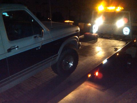 1986 Ford Bronco - Ford Bronco being towed at night, with the tow truck's lights illuminated.
