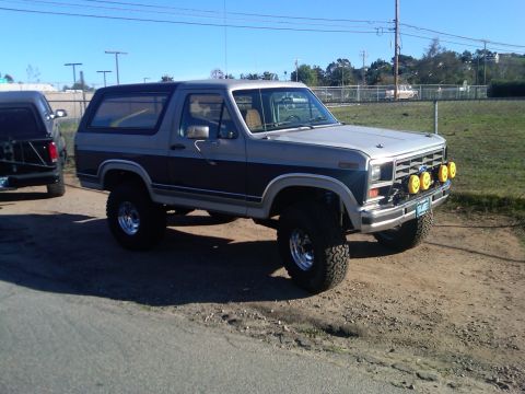 1986 Ford Bronco - This lifted Ford Bronco has a two-tone paint job and auxiliary lighting on the front grille.