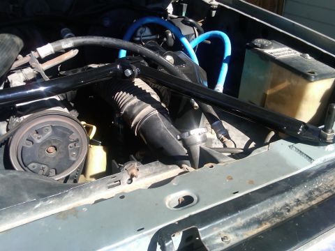 1986 Ford Bronco - Engine bay of a 1986 Ford Bronco, blue hoses and a black brace.