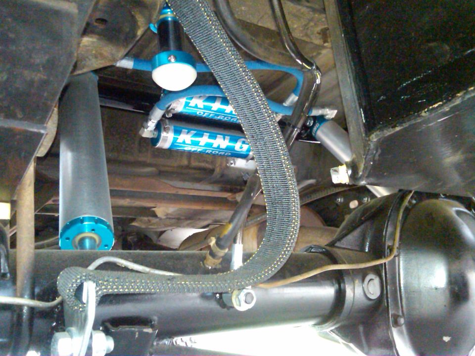 Close-up of blue King Off-Road shocks and suspension parts on a vehicle underside