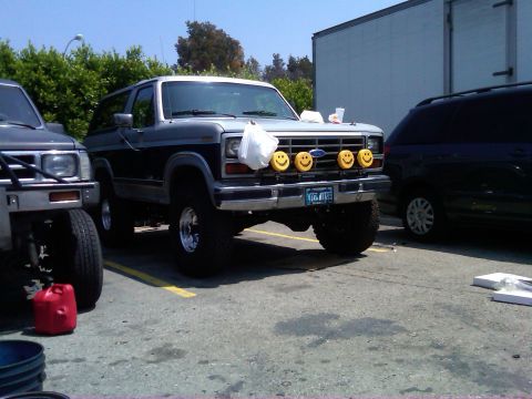 1986 Ford Bronco - 1986 Ford Bronco parked next to another vehicle, custom smiley face lights.