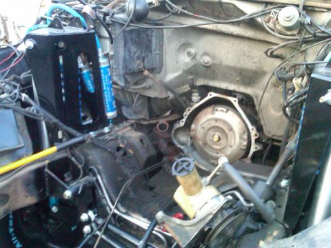 1986 Ford Bronco - The engine bay of a vehicle is shown with the transmission removed, revealing internal components and suspension parts.