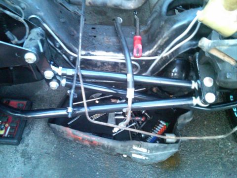1986 Ford Bronco - Tools are laid out near the suspension components of a vehicle's undercarriage.