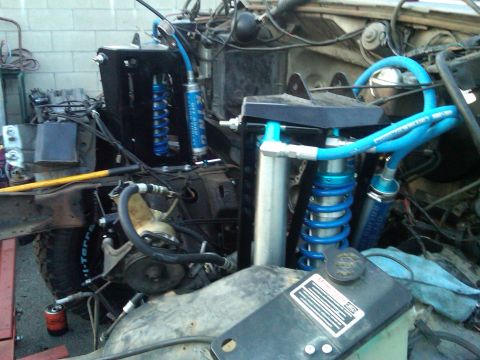 1986 Ford Bronco - Custom off-road suspension components, including blue coilover shocks and hydraulic lines, are visible in this close-up.