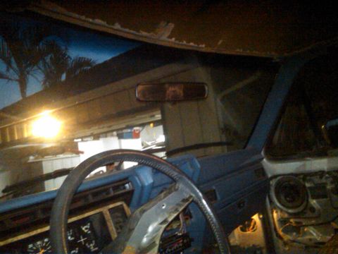 1986 Ford Bronco - Interior view of a vehicle, showing the dashboard and steering wheel, with visible damage to the headliner.