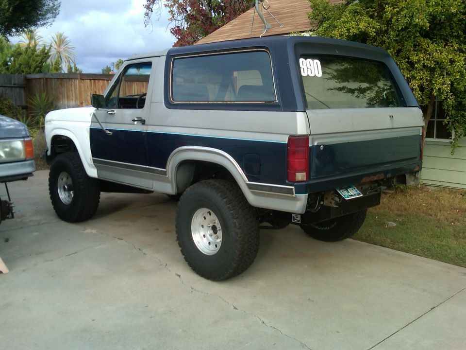 1986 Ford Bronco, two-tone paint, lifted suspension, off-road tires, number 990 on rear window