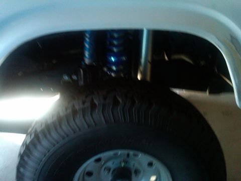 1986 Ford Bronco - A close-up view of a vehicle's tire and suspension system, showing a blue shock absorber.