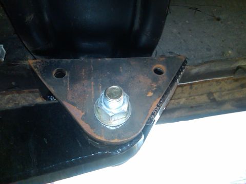 1986 Ford Bronco - A close-up view of a vehicle's suspension bracket, showing rust and a large bolt securing it to the frame.