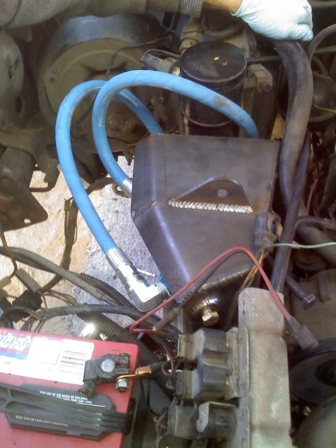 1986 Ford Bronco - This image shows various engine components, including hoses, a custom metal bracket, and a car battery.