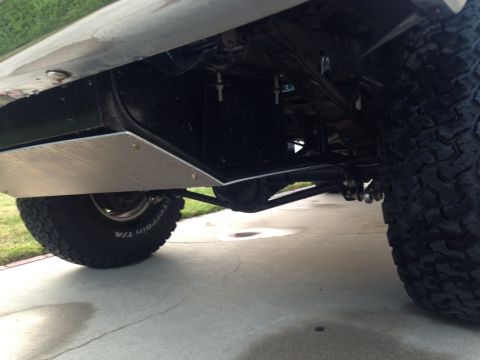 1986 Ford Bronco - The undercarriage of a vehicle shows a skid plate and off-road tires.