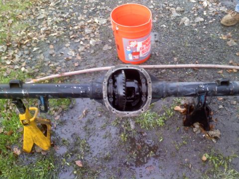 1986 Ford Bronco - Differential housing removed from a vehicle, resting on jack stands outdoors.