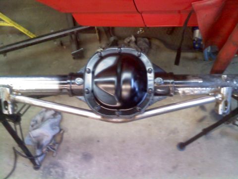 1986 Ford Bronco - Close-up view of a rear differential and polished suspension parts, with a red body panel visible above.