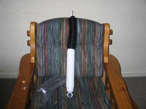 1995 Ford Bronco - New shock absorber resting on a chair, ready for installation.