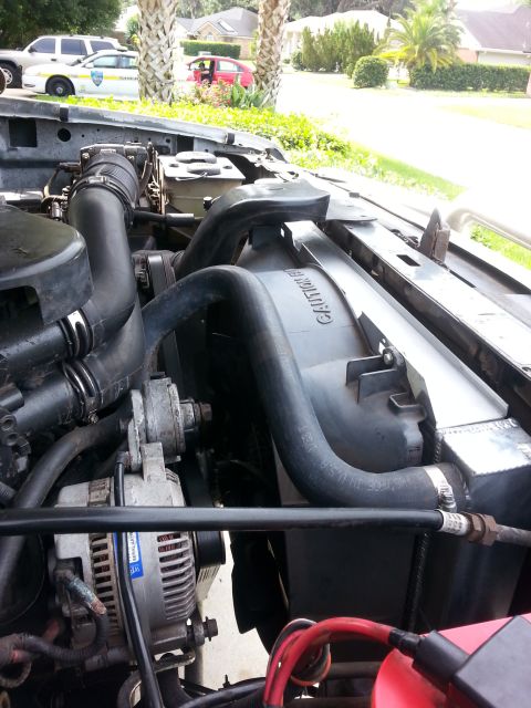 1992 Ford Bronco - Close-up view of the engine bay, focusing on the radiator and alternator. Other vehicles are visible in the background.