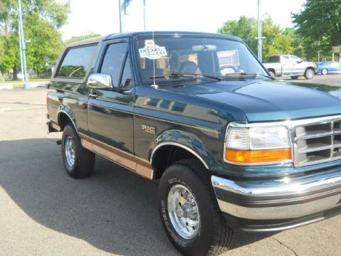 1994 Ford Bronco - This 1994 Ford Bronco is shown from a 3/4 front angle, highlighting its dark green paint and tan body trim.