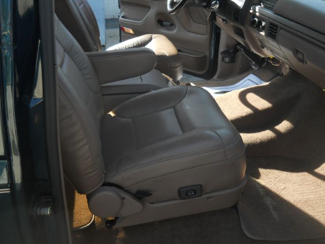 Interior shot of a vehicle's front seats, showing tan leather upholstery and armrests