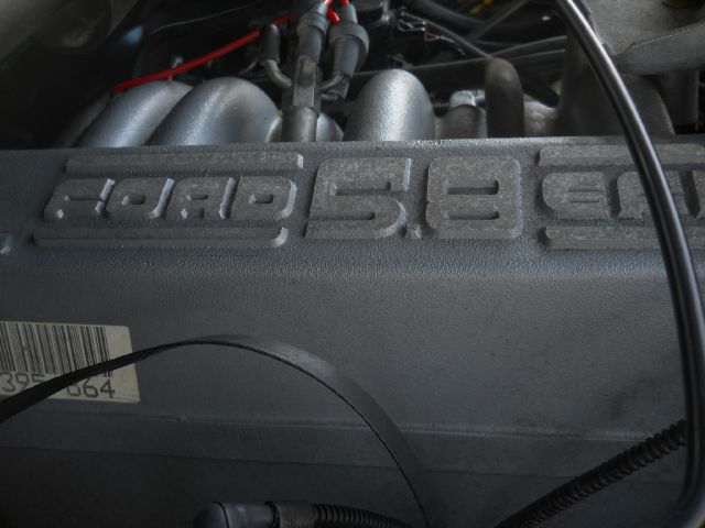 Close-up of a Ford 5.8L engine valve cover with some hoses and wiring