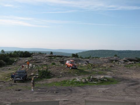 1979 Ford Bronco - Two off-road vehicles are parked on a rocky landscape under a clear blue sky.