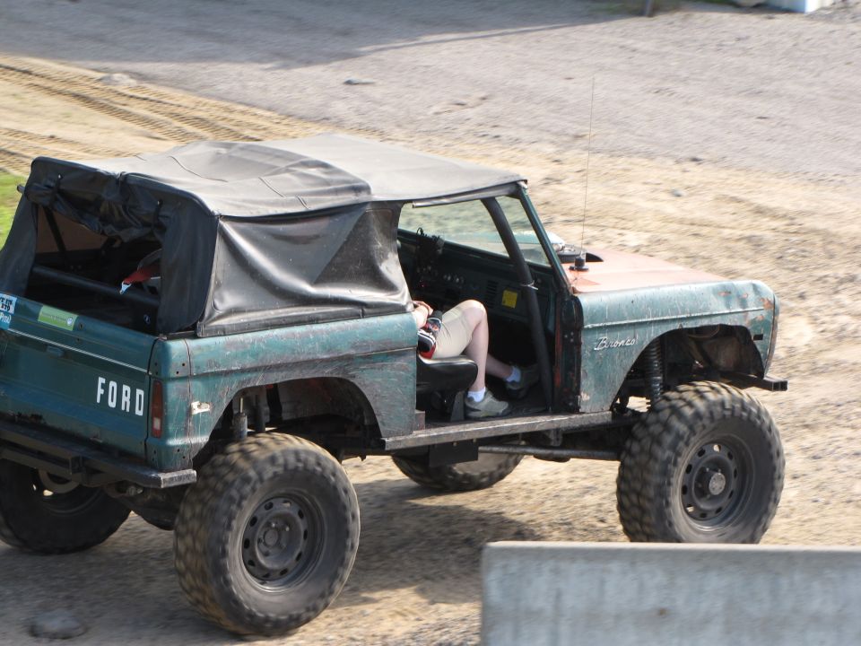 Green 1979 Ford Bronco with soft top and large tires, side view