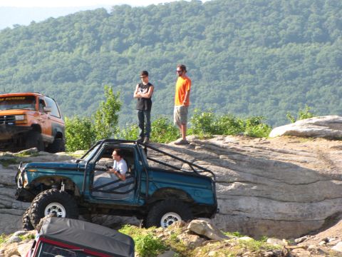 1979 Ford Bronco - A teal 1979 Ford Bronco navigates a rocky trail with two people observing from above.