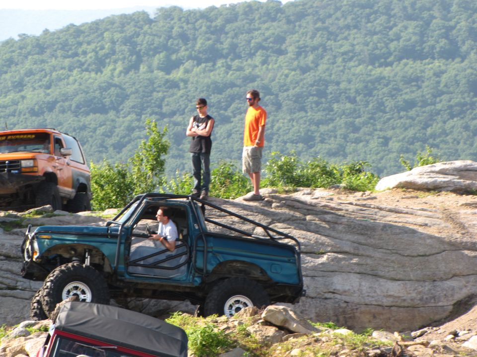 Teal 1979 Ford Bronco with roll cage on rocky terrain
