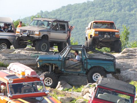 1979 Ford Bronco - Several modified off-road vehicles tackle a challenging rocky incline during an outing.