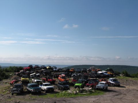 1979 Ford Bronco - A large collection of off-road vehicles are gathered on a hilltop with a scenic view of the surrounding landscape.