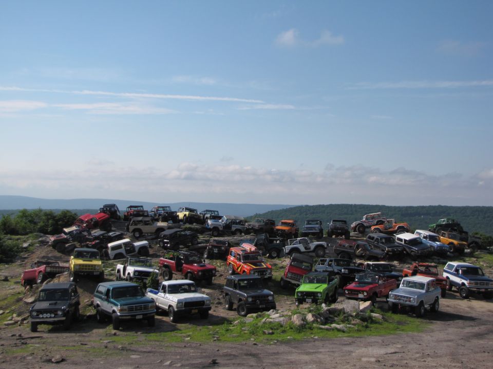 1979 Ford Bronco and other off-road vehicles parked on a hill under a blue sky