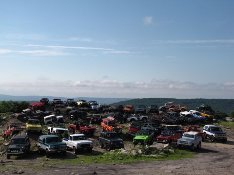1979 Ford Bronco - A large gathering of off-road vehicles, predominantly Ford Broncos, are parked on a scenic overlook.