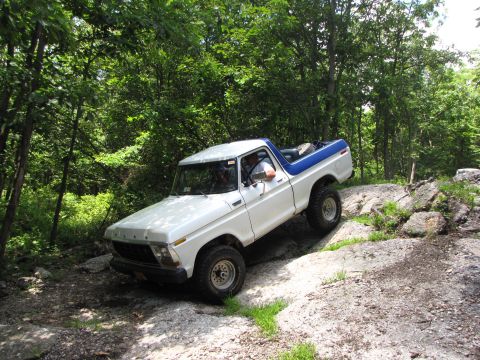 1979 Ford Bronco - This 1979 Ford Bronco is shown tackling a challenging rocky path in a wooded area.