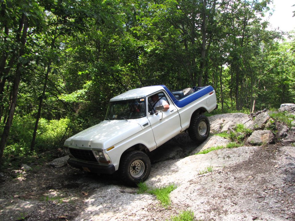 White and blue 1979 Ford Bronco navigating a rocky off-road trail