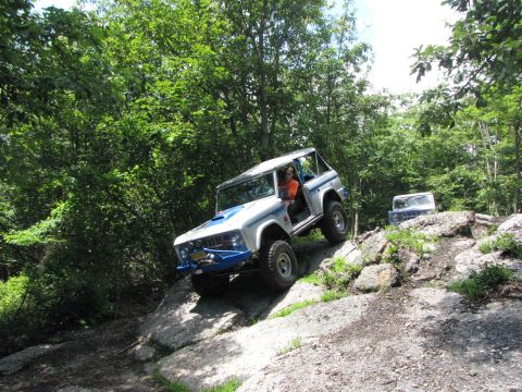 1979 Ford Bronco - Two Ford Broncos navigate a challenging off-road course with steep, rocky inclines.