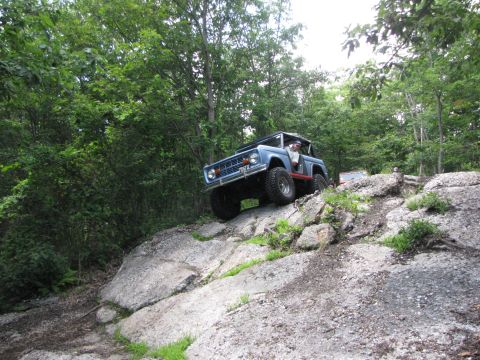 1979 Ford Bronco - A blue Ford Bronco navigates a challenging rocky trail, with another vehicle visible further up the path.