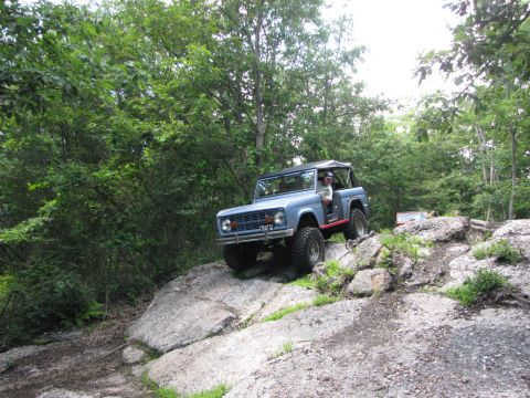 1979 Ford Bronco - A blue 1979 Ford Bronco tackles a challenging rocky trail, demonstrating its off-road capabilities.