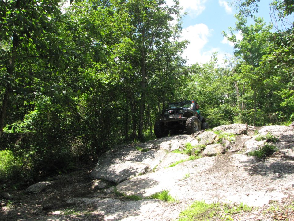 Off-road vehicle climbing rocks on a wooded trail