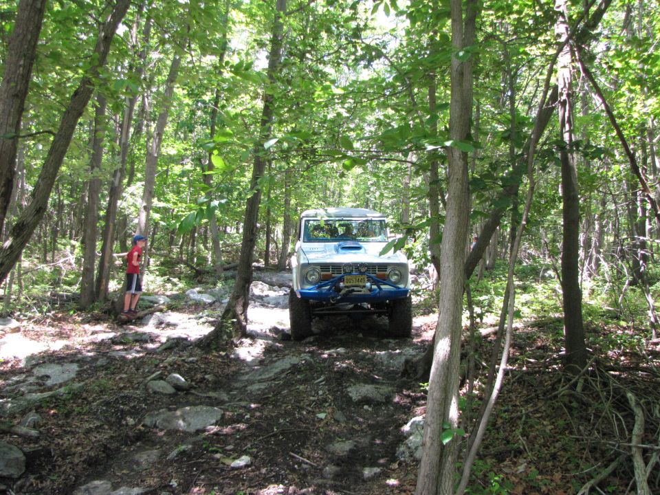 White 1978 Ford Bronco with blue roll cage and winch on rocky trail