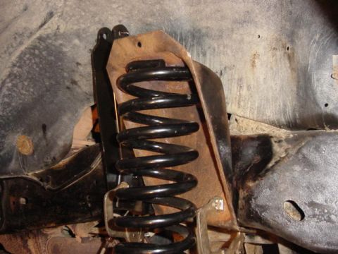 1992 Ford Bronco - Close-up of a vehicle's front suspension coil spring and its mounting bracket.