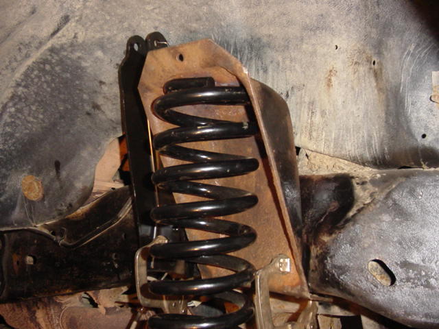 Front suspension coil spring and rusty metal mount, part of a vehicle's undercarriage