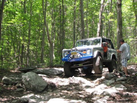 1979 Ford Bronco - This modified Ford Bronco is tackling a challenging off-road course in a wooded area.