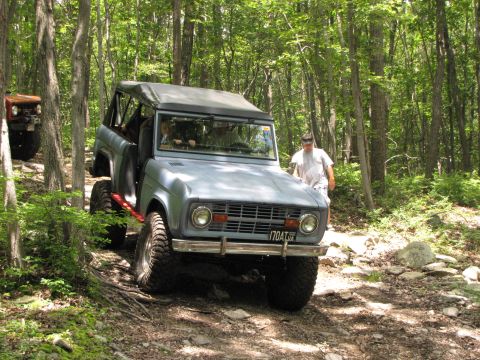 1979 Ford Bronco - A light blue Ford Bronco navigates a rocky, wooded trail with another vehicle following.