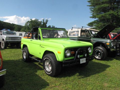 1979 Ford Bronco - Lime green Ford Bronco with black roll cage and bull bar, parked at an outdoor event with other vehicles.
