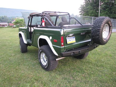 1979 Ford Bronco - This green Ford Bronco is shown from the rear with its hood open and a spare tire on the back.