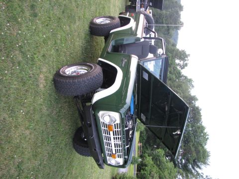 1979 Ford Bronco - This green Ford Bronco is shown with its hood open, parked on a grassy area next to another vehicle.