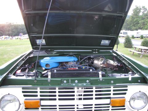 1979 Ford Bronco - The engine bay of a green 1978 Ford Bronco is visible with the hood raised, revealing the engine and air cleaner.