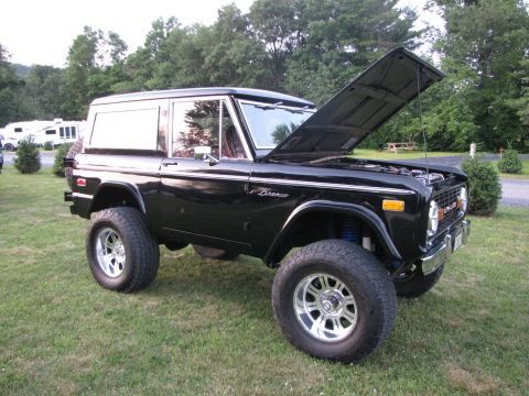 1979 Ford Bronco - This black 1979 Ford Bronco features a lifted suspension and custom wheels, with its hood open for display.