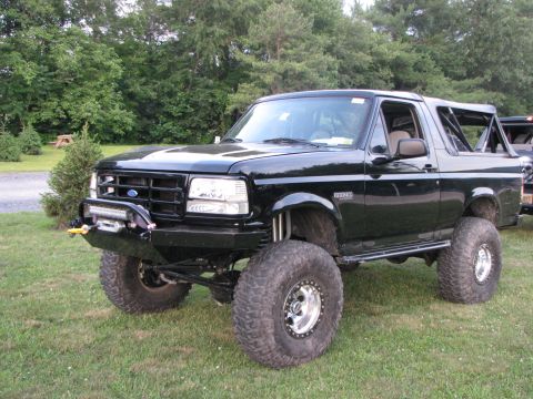 1979 Ford Bronco - Modified black Ford Bronco with large off-road tires and custom front bumper.