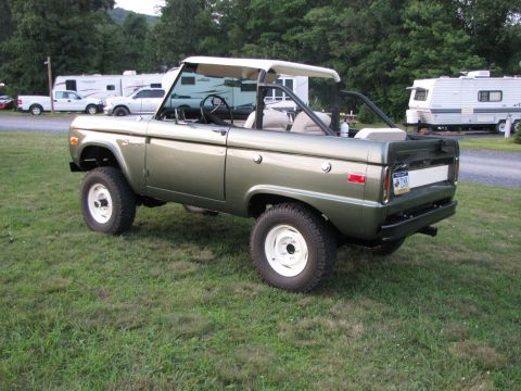 1979 Ford Bronco - A 1978 Ford Bronco with a removable white top sits on a grassy field next to RVs.