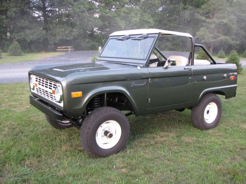 1979 Ford Bronco - This 1979 Ford Bronco features a classic green exterior with a white removable top and white wheels, presented in a three-quarter front per…