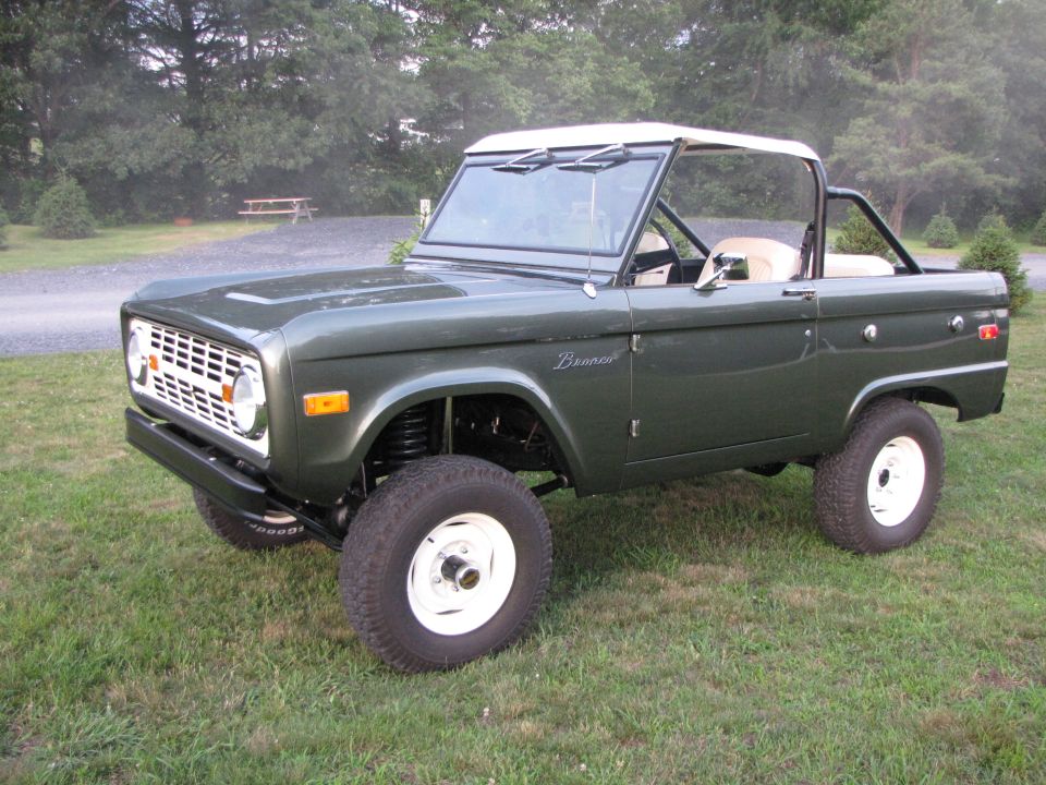 Green 1979 Ford Bronco with white top and white wheels, 3/4 front view